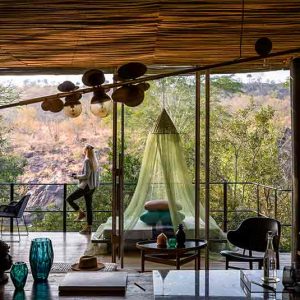A person standing on a deck of a room at Singita Sweni