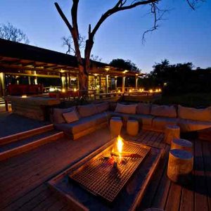 Main deck with fireplace in the evening at Vumbura Plains