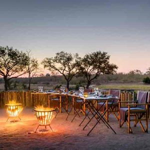 Several fires burning surrounded by tables and chairs for dining