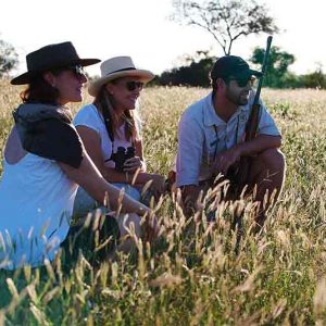 People crouched in long grass while on walking safari at Londolozi