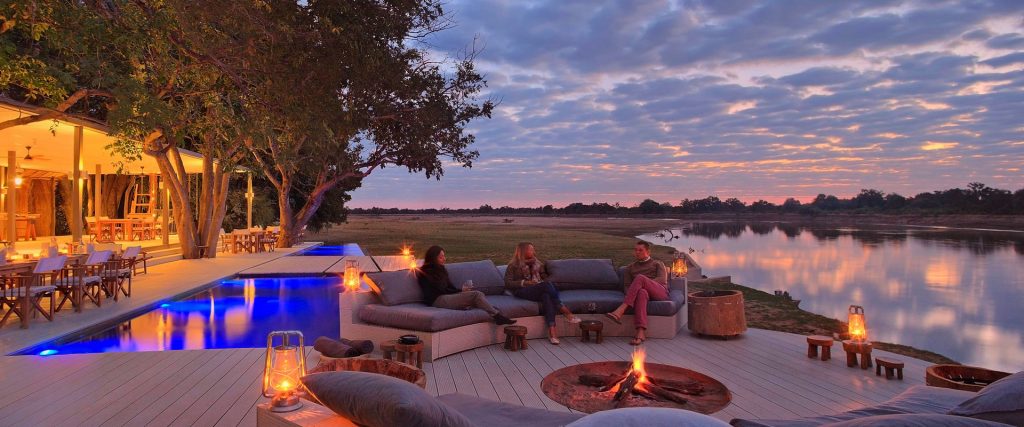 People sitting around a burning fire on the banks of the Luangwa river