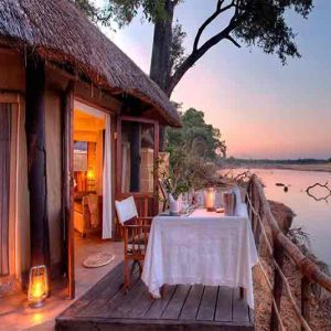 dining table on the deck of a chalet next to a river