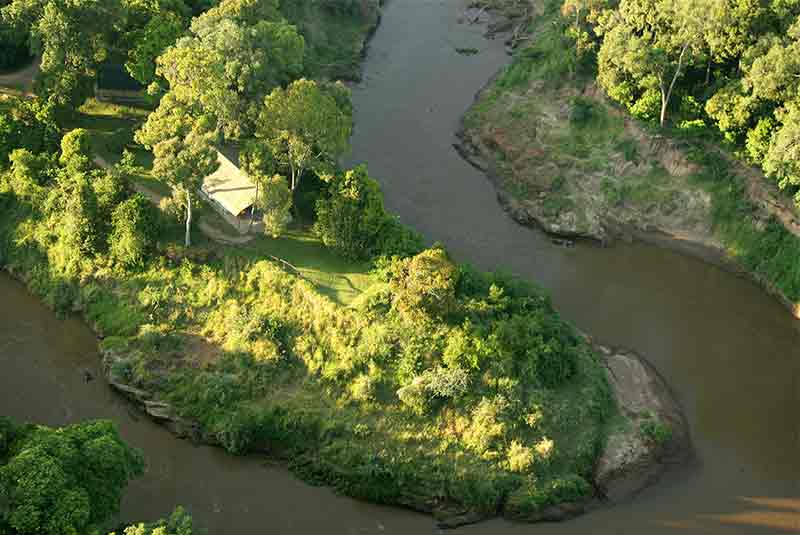 An aerial view of a safari tent surrounded by a winding river