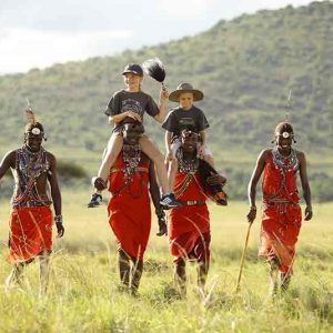 Masai tribesmen with children walking in grass on a kenya family holiday